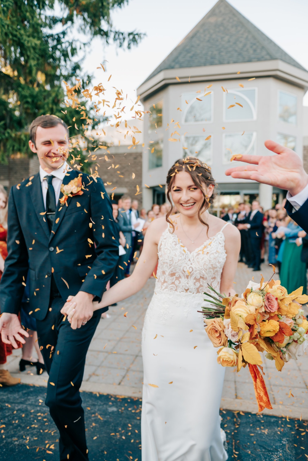 Newlyweds walk through a shower of golden petals after the ceremony